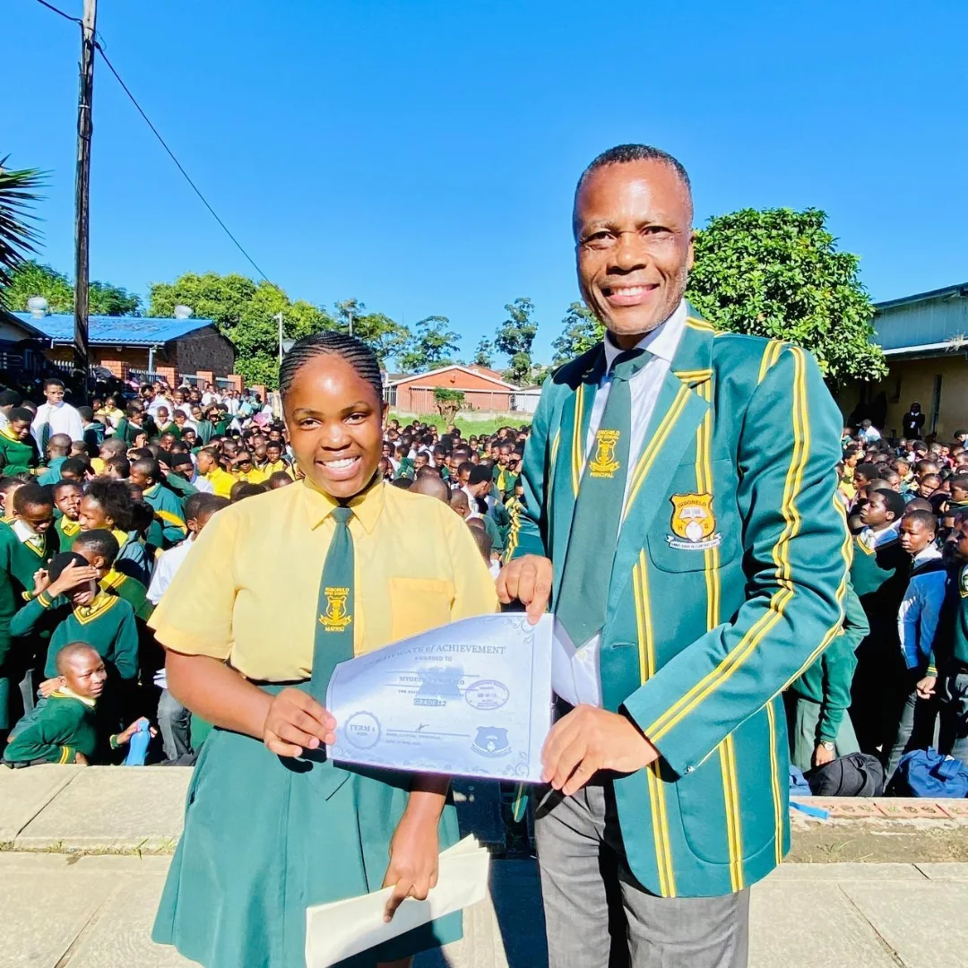 Principal of Isibonelo High School with a learner receiving a Certificate of Achievement
